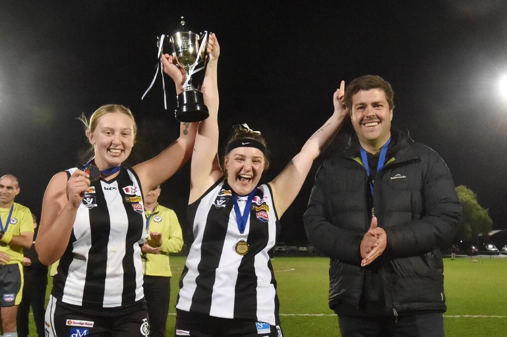 Magpies skipper Emily Cooper (left) and Eloise Gretgrix lift the cup next to senior coach Jordan Cochrane. Picture by Darren Howe 