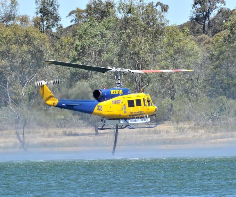 Truck in the sky: A firefighting helicopter fills up from Crusoe Resevoir in Big Hill yesterday. Picture: NONI HYETT