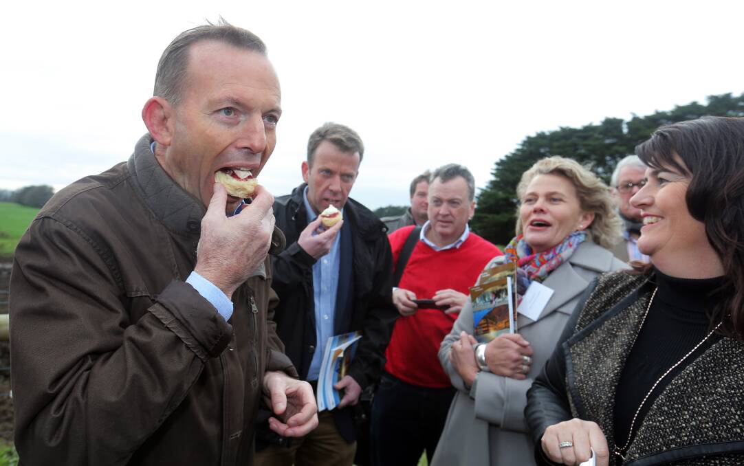 Prime Minister Tony Abbott pleases the crowd by eating a scone at the launch of the Agricultural Competitiveness White Paper in the state's south west on Saturday.