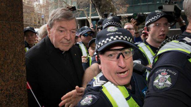 The cardinal leaves court, surrounded by police and a media pack. Photo: Jason South