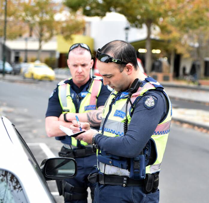 ON PATROL: Senior Constable Dave Sanders and Sergeant Mick McCrann write up a driver's details. Bendigo police will be conducting extra patrols on high-risk roads until June. Picture: DARREN HOWE