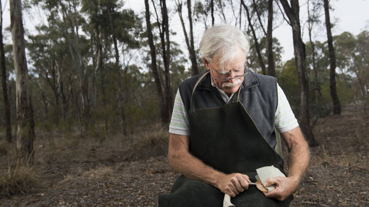 Cam Cowled chipping away with a tool he made during an experimental archaeology course. Picture: DARREN HOWE