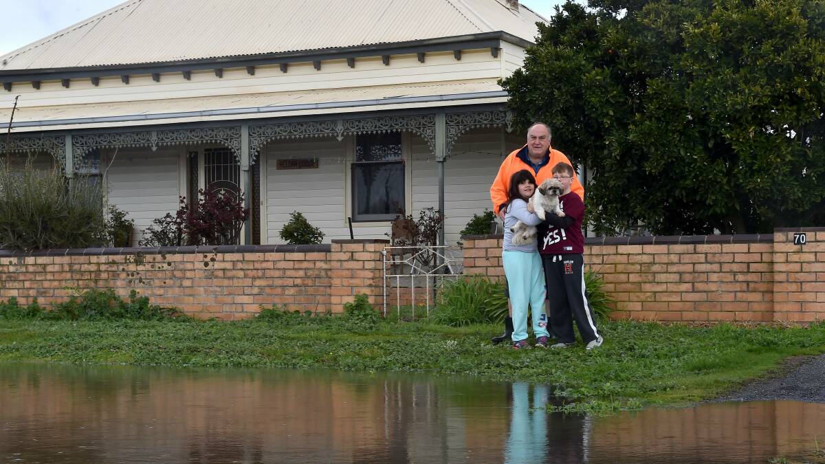 WORRY: Danny McIver, Charlotte and Luke Wandin watch as water flowed outside the
front of the house in Carisbrook on September 14. Pictures: NONI HYETT