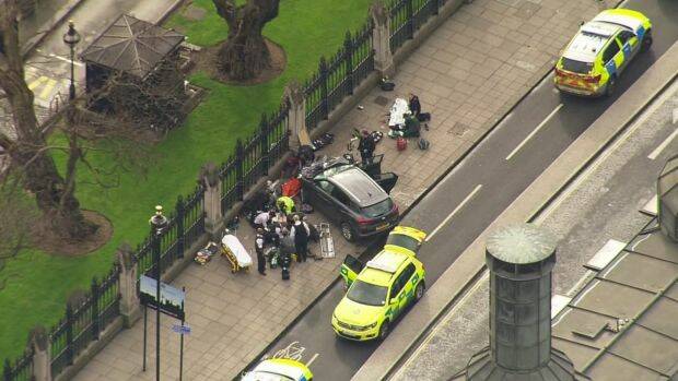 In this image taken from video, police officers gather around a car adjacent to Houses of Parliament in London. Photo: AP