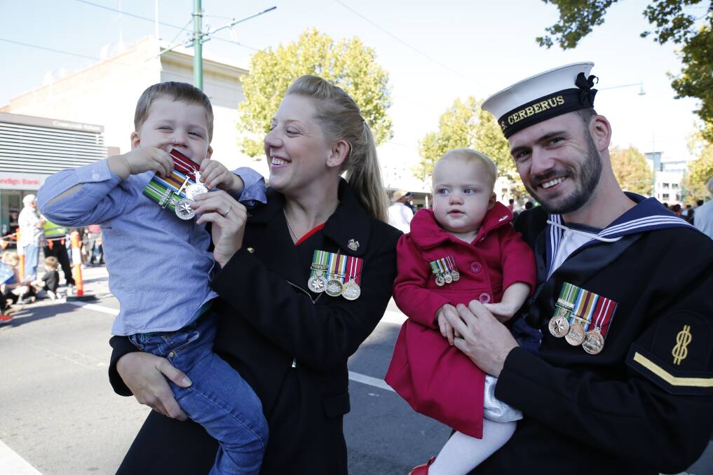 Dexter, 3, plays peek-a-boo with his family's war medals. It gets a smile from Belinda Kelso, one-year-old Abigael, and Able Seaman Marine Technician Bryce Leslie. Picture: EMMA D'AGOSTINO