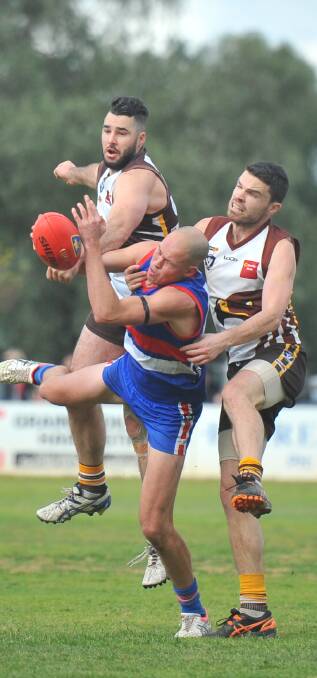 SANDWICHED: North Bendigo's Brady Herdman competes against Huntly defenders Brad Chalmers and Chris Gleeson. Pictures: LUKE WEST