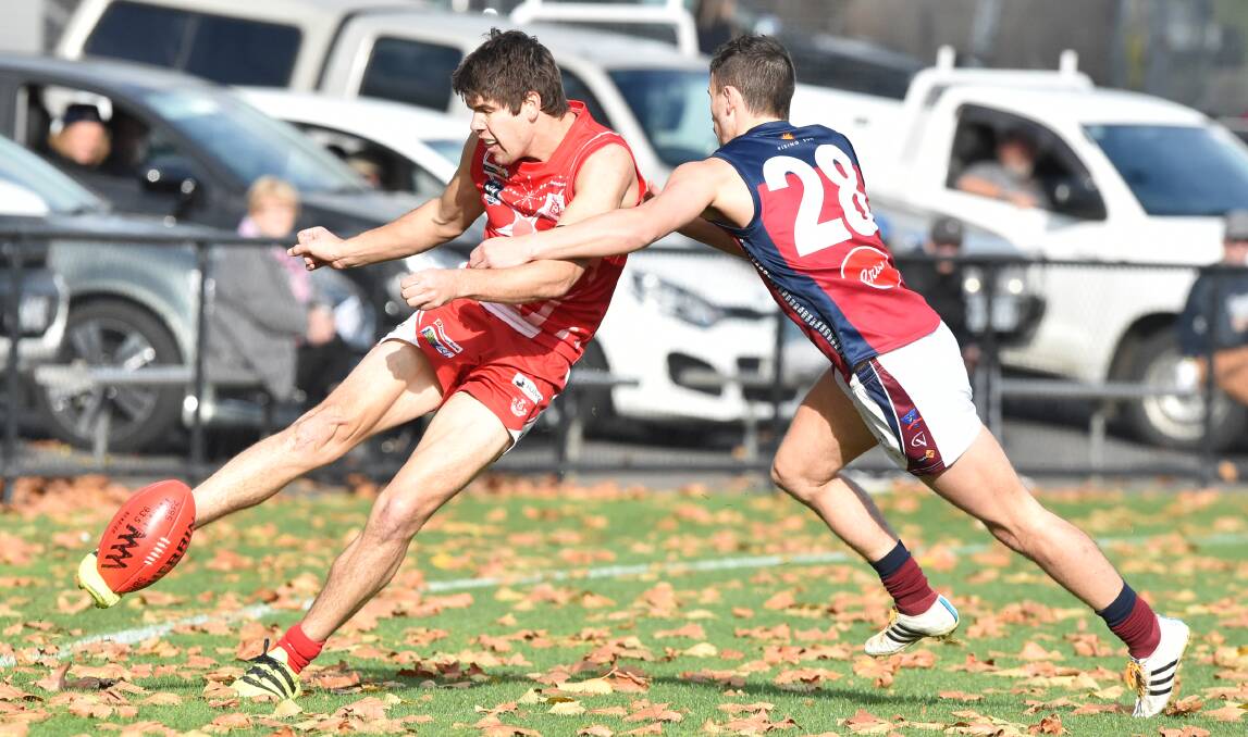 CLEARING KICK: South Bendigo's Isaiah Miller gets boot to ball under pressure from Sandhurst's Galen Munari at the Queen Elizabeth Oval on Saturday. The Bloods were 30-point winners to improve to 5-1. Picture: DARREN HOWE
