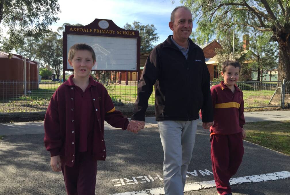 SAFE CROSSINGS: Axedale Primary School principal Lex Johnstone crosses the McIvor Highway, which fronts the school, with students Matt Brown and Sam Doak. Pictures: JOSEPH HINCHLIFFE
