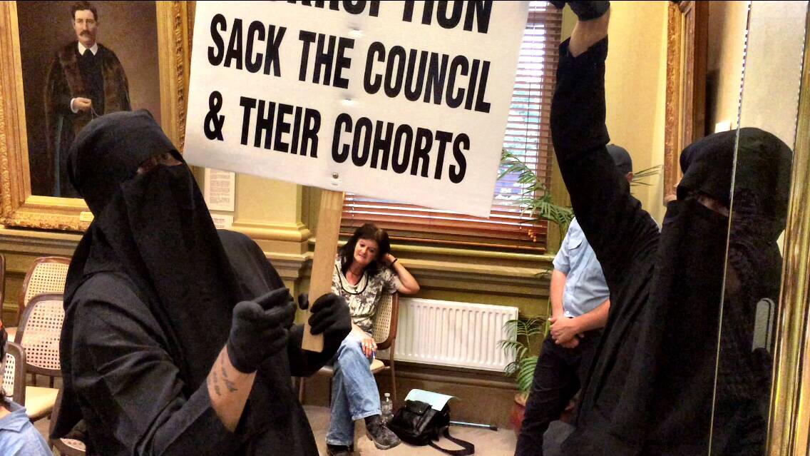 Two men in burkas protest during the council meeting. 