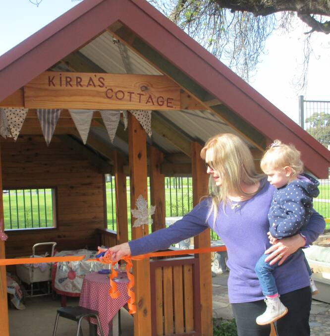 REWARDING: Simone Anstee, with Nikirra Sim, cuts the ribbon to officially open Kirra's Cottage in honour of her daughter.