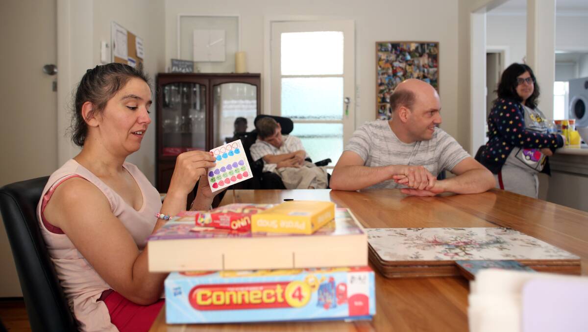 Yvonne Caldow and Simon Mahlstedt prepare to play a board game at the Bendigo L'Arche House of Welcome. In the background Anthony Smith and Mary Begg watch on. Picture: GLENN DANIELS