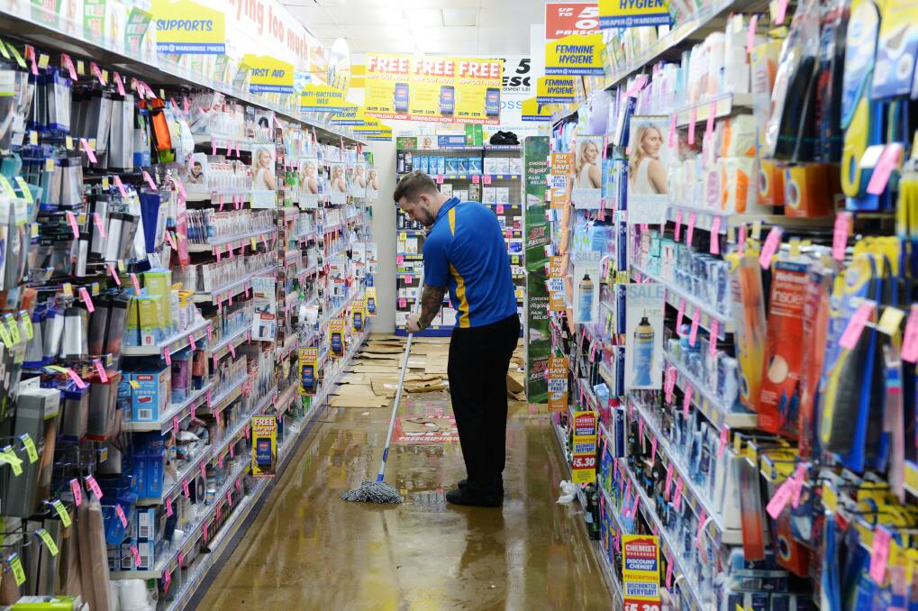 Clean up at the Chemist Warehouse on Mitchell Street after flooding. Picture: DARREN HOWE