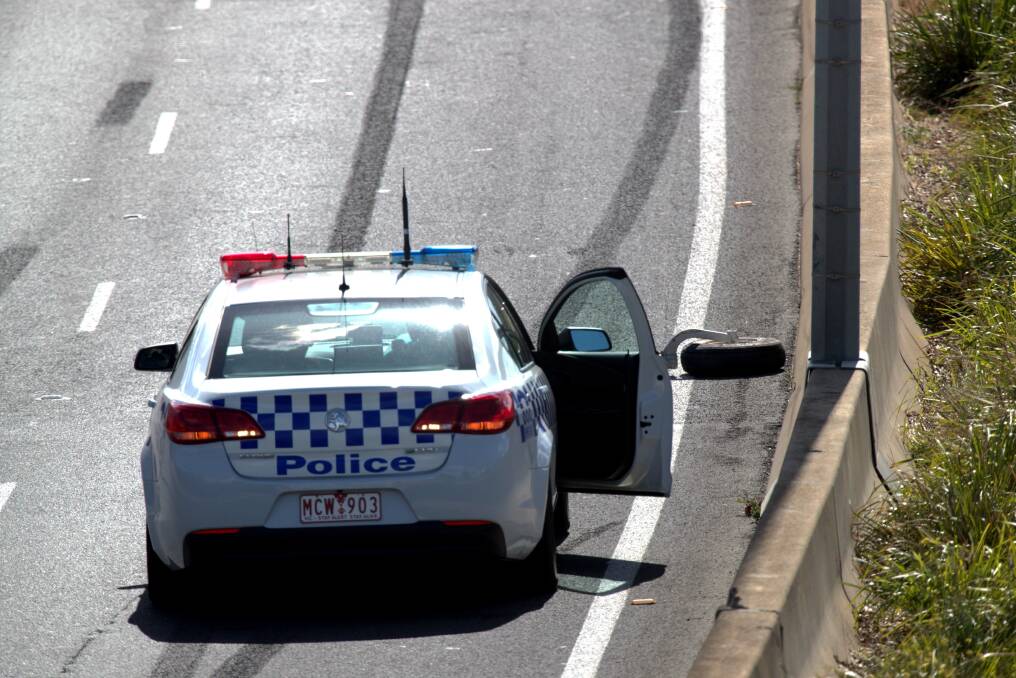 Police investigate the debris on the freeway near to the crash site at Essendon Airport. Photo: Jason South