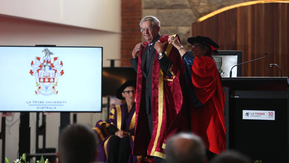 Richard Larkins receives his chancellor gown from Adrienne Clarke.