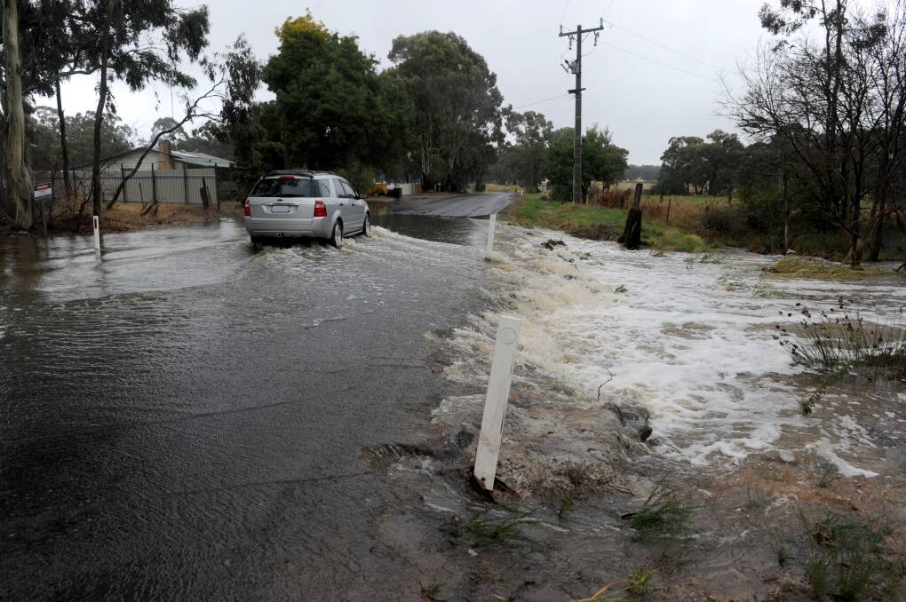 A vehicle crosses a flooded road on a rainy day in April last year, Bendigo's wettest April on record. Picture: NONI HYETT
