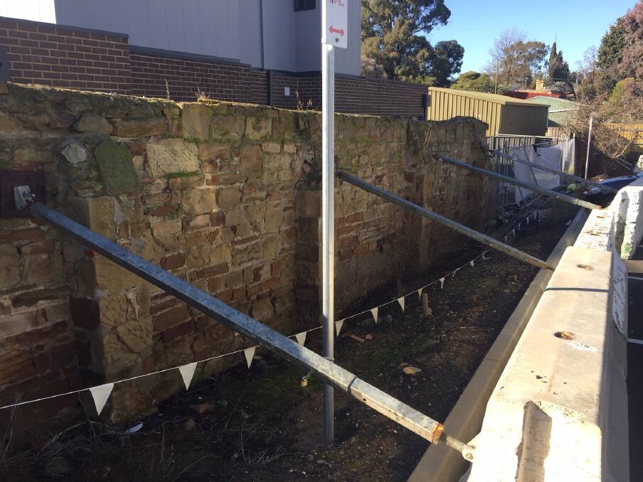 HELPING HAND: The 19th century stone wall partially demolished during construction of the St John of God hospital car park, seen here supported by metal rods attached to concrete bollards.