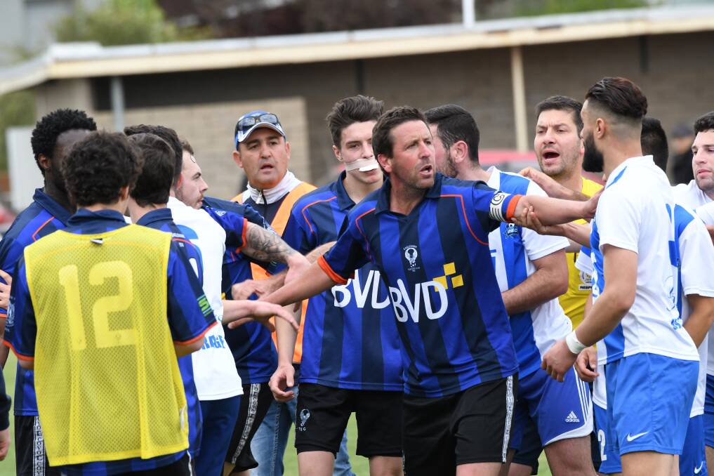 STAND BACK: Eaglehawk coach Greg Thomas attempts to break up Shepparton United and Eaglehawk players during a preliminary final on Sunday. Pictures: NONI HYETT