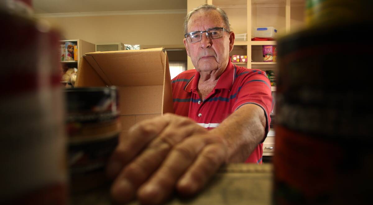 HUNGRY: UnitingCare Bendigo volunteer Allan Shearn searches his organisation's ever-shrinking shelf of food for donations. Picture: GLENN DANIELS