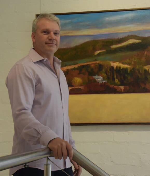 NEW LIFE: Valentine's Antiques manager Peter Valentine in his shop's new gallery space, featuring landscapes by artist Jeff Makin. The store specialises in matching old furniture with contemporary art. Picture: MARK KEARNEY