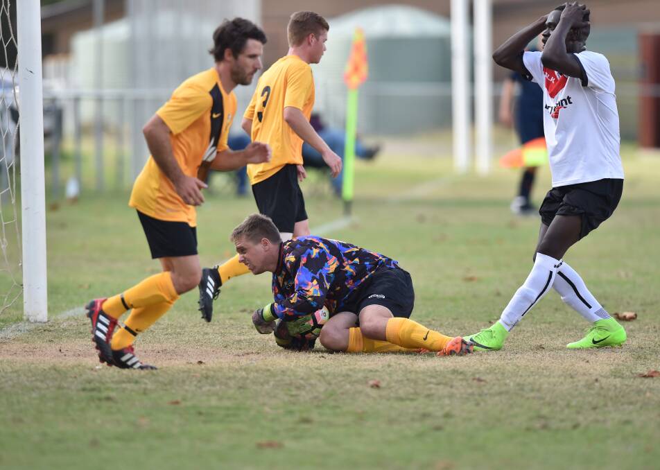 Colts United goal keeper Phil Berry grabs the ball in front of Golden City striker Godwill Basha. Picture: GLENN DANIELS