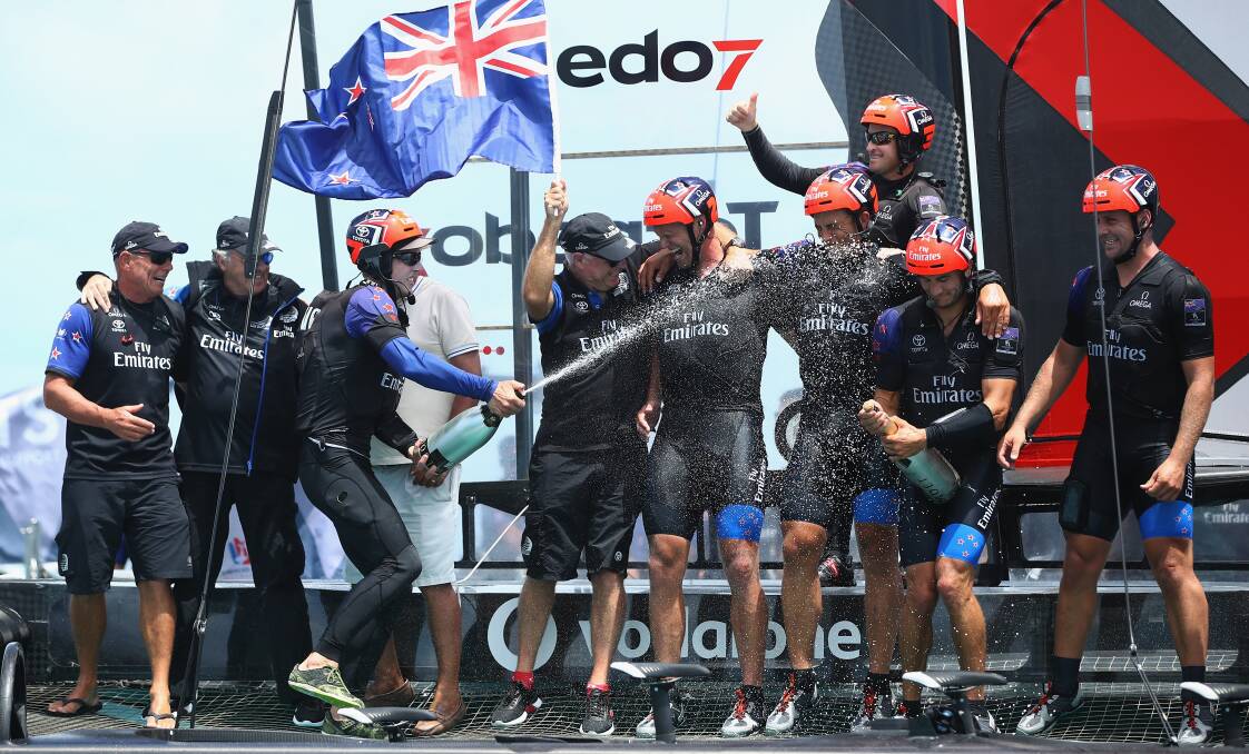 Glenn Ashby, back, gives everyone the thumbs up after Team NZ's triumph. Picture: GETTY IMAGES