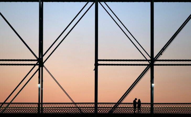 A couple stands on the Walnut Street Bridge as the sun rises during the final day of the Ironman 70.3 World Championship on Sunday, Sept. 10, 2017, in Chattanooga, Tenn. (C.B. Schmelter/Chattanooga Times Free Press via AP)