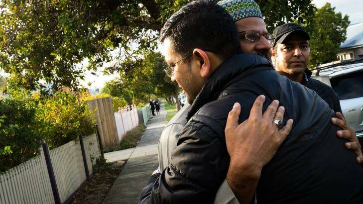 Imam Mohammad Ramzan embraces members of the Islamic community outside the burnt-out mosque. Photo: Chris Hopkins