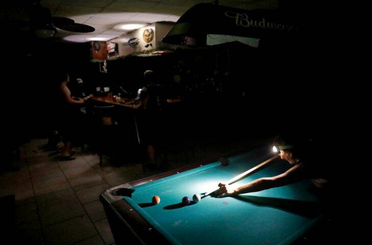 Lisa Borruso plays pool using a headlamp as the power remains out following Hurricane Irma at Gators' Crossroads in Naples, Fla., Monday, Sept. 11, 2017. Statewide, an estimated 13 million people, or two-thirds of Florida's population, remained without power. That's more than the population of New York and Los Angeles combined. Officials warned it could take weeks for electricity to be restored to everyone. (AP Photo/David Goldman)