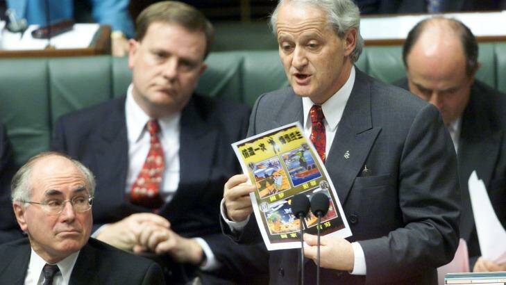 Philip Ruddock  speaks about illegal boat people in Parliament, while  holding a poster on the subject. Photo: Paul Harris