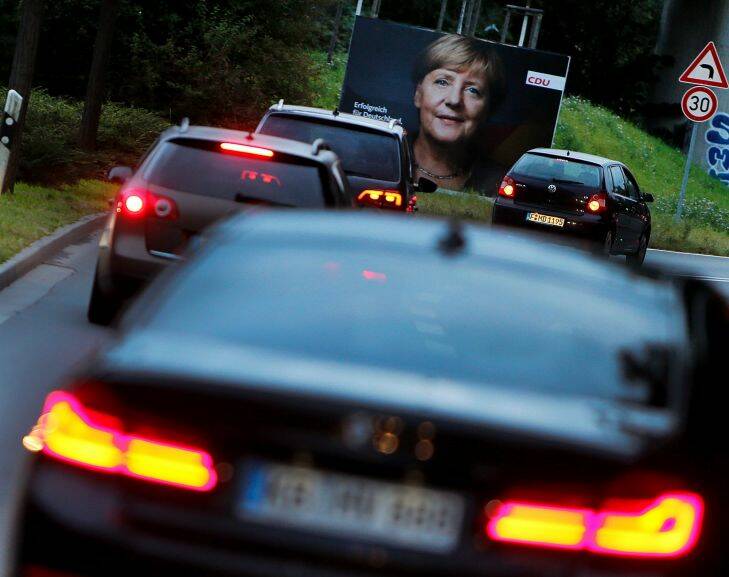 Cars pass an election poster showing German Chancellor Angela Merkel in Frankfurt, Germany, Tuesday, Sept. 19, 2017. German elections will be on Sunday Sept. 24. (AP Photo/Michael Probst)