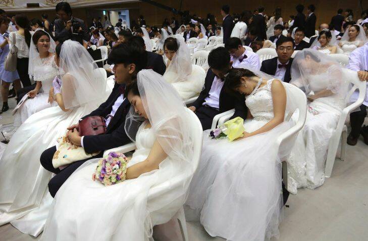 Brides takes a nap before a mass wedding ceremony at the Cheong Shim Peace World Center in Gapyeong, South Korea, Thursday, Sept. 7, 2017. About 4,000 South Korean and foreign couples exchanged or reaffirmed marriage vows in the Unification Church's mass wedding arranged by Hak Ja Han Moon, wife of the late Rev. Sun Myung Moon, the controversial founder of the Unification Church. (AP Photo/Ahn Young-joon)