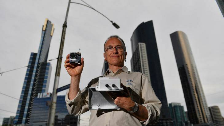 EPA expert Dr Anthony Boxshall holds a small air quality sensor, now installed on Queens Street Bridge lamps. Photo: Joe Armao