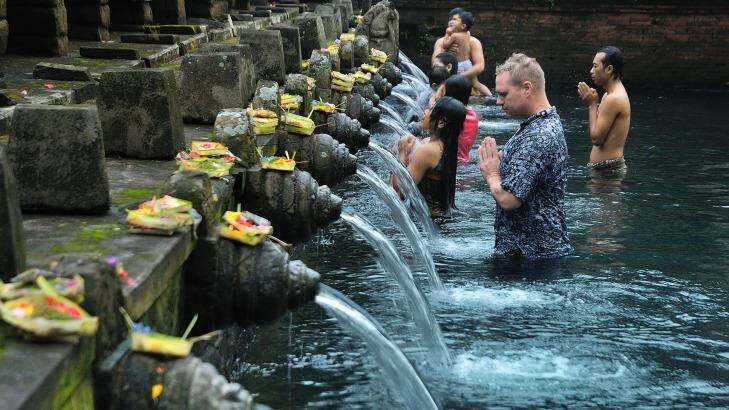 Healing waters: A visitor joins the Balinese at the Pura Tirta Empul. Photo: Supplied