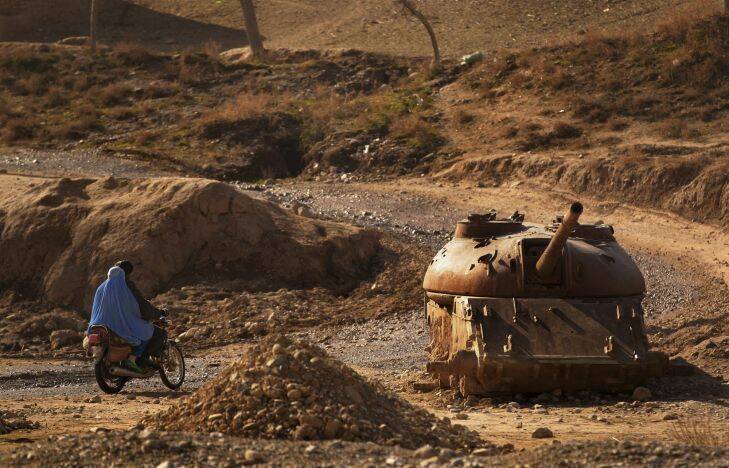 URUZGAN- DAILY LIFE
A man and woman ride past an old destroyed Russian tank at Sarkhom Manda, Tarin Kowt District, Uruzgan Province, Afghanistan. 26th January, 2013. Photo: Kate Geraghty