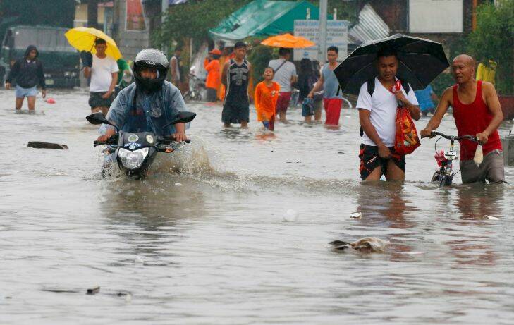 Residents wade through a flood road as they go on their daily business after overnight rains brought about by Tropical Depression Maring inundated low-lying areas Tuesday, Sept. 12, 2017 in Bacoor township, Cavite province, south of Manila, Philippines. Maring is expected to make a landfall Tuesday in northeastern Philippines prompting authorities to suspend classes and some government offices to close in affected areas, including metropolitan Manila. (AP Photo/Bullit Marquez)