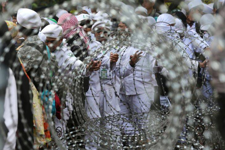 Muslim protesters are seen through razor wire barricades during a rally against the persecution of Rohingya Muslims outside the Myanmar's Embassy in Jakarta, Indonesia, Wednesday, Sept. 6, 2017. Several thousand people marched in Indonesia's capital on Wednesday, calling on the government of the world's most populous Muslim nation to put more pressure on Myanmar to halt the persecution of its Rohingya Muslim minority. (AP Photo/Tatan Syuflana)