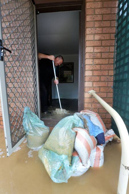 Flooded: Glen Rankin cleans his sister's unit. Picture BRENDAN McCARTHY