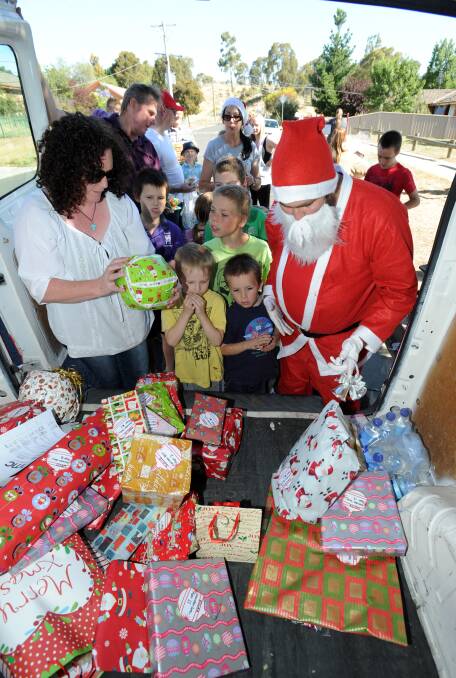 DELIVERY: Santa hands out presents to children in Long Gully. Picture: JODIE DONNELLAN 
