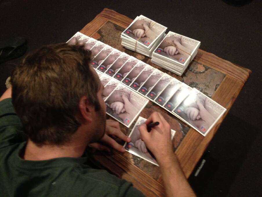 MUSICIAN: John Trager signs the CDs. Picture: CONTRIBUTED