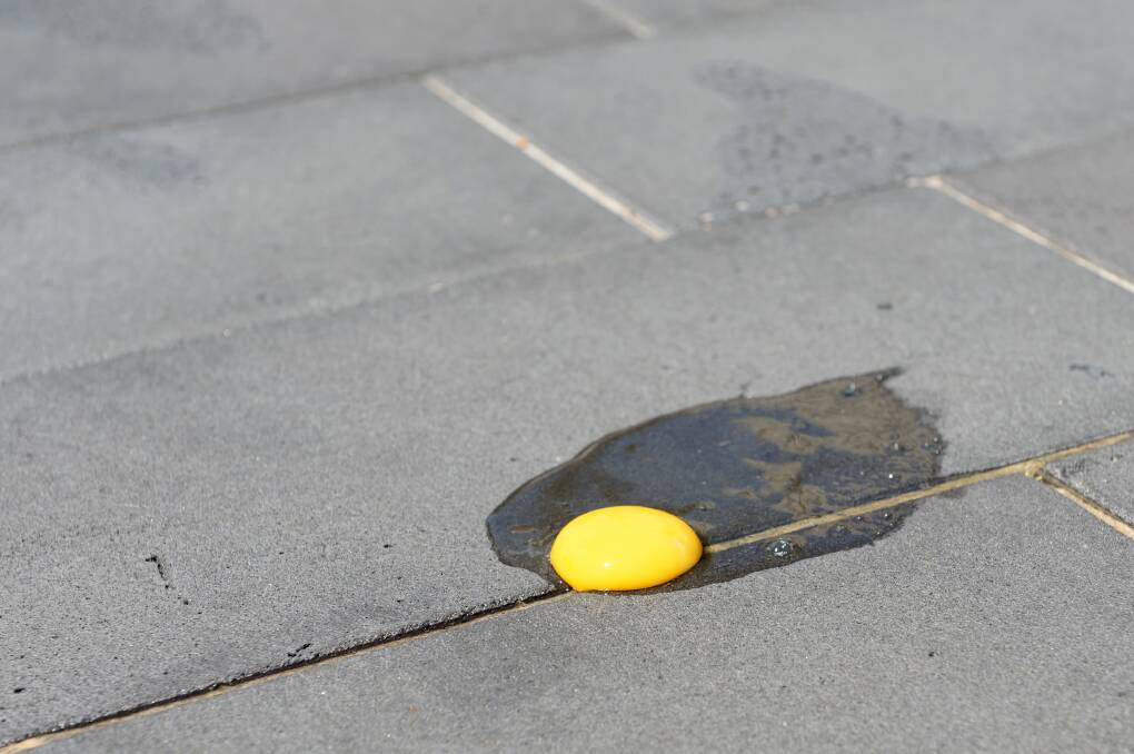 Bendigo Advertiser journalist Josh Fagan attempts to cook an egg on the pavement during Tuesday's heat. Picture: JIM ALDERSEY