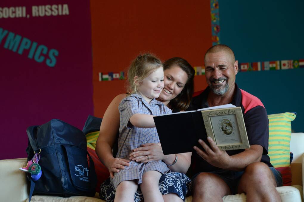 Lucy Newton with her mum Trudie Newton who sits next to her dad Greg Kane, holding a photo album with Greg's late father Frank Kane. The 4 all attended prep at Holy Rosary Primary School between 1936 and 2014. Picture: JIM ALDERSEY
