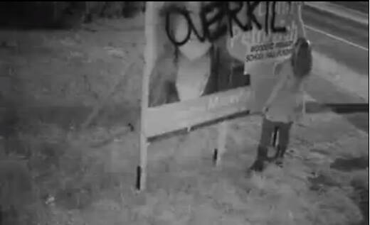 A woman is caught on camera defacing the sign of Liberal candidate for Macedon Donna Petrovich, in Woodend.
