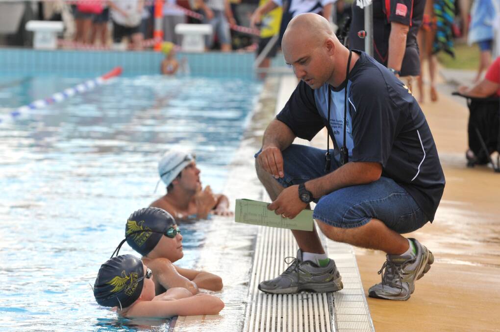 Bendigo Hawks coach Ashley Wain gives some tips to Olivia Wright and Mitchell Sherlock before their next race at the 2012 Victoria Country titles at Bendigo Aquatic Centre. 