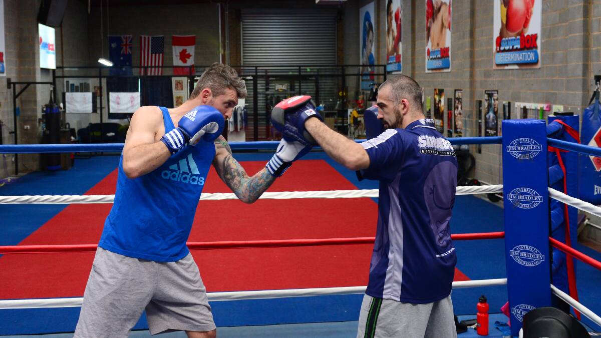 Ewen Jones strikes the pads held by trainer and Olympic boxer Lynden Hosking during a workout at Supabox in Bendigo. Picture: JIM ALDERSEY