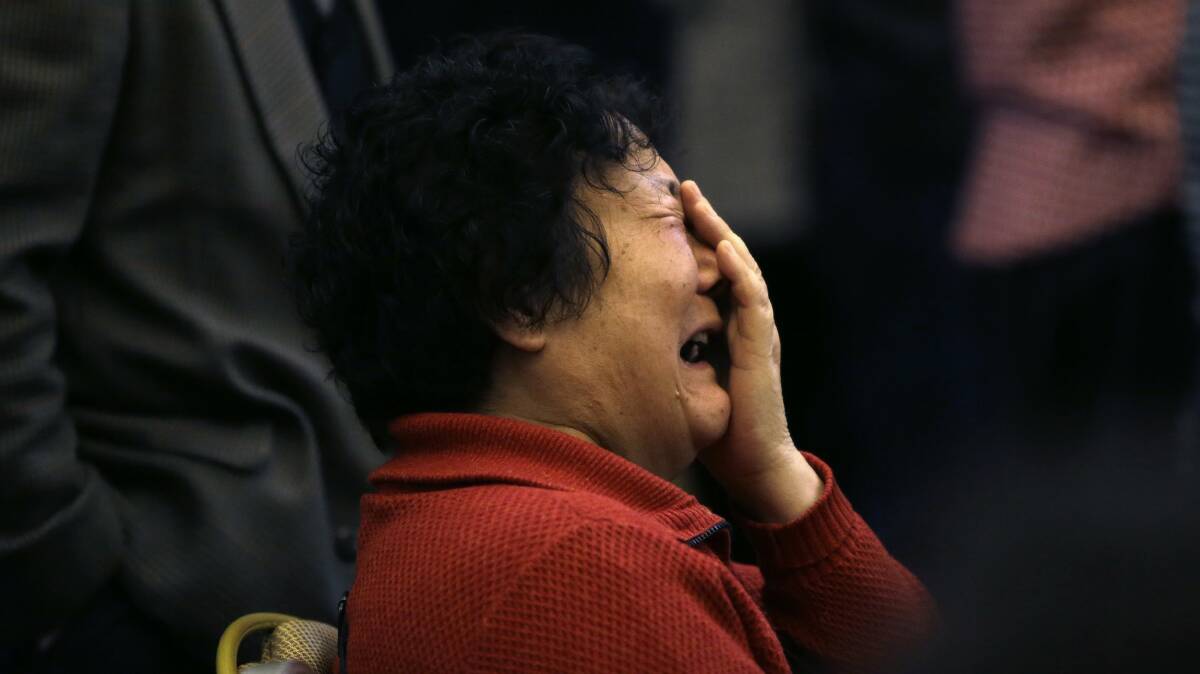 A family member of a passenger onboard Malaysia Airlines Flight MH370 covers her face as she cries after a routine briefing given by Malaysia Airlines at Lido Hotel in Beijing, March 22, 2014. Photo: Reuters.