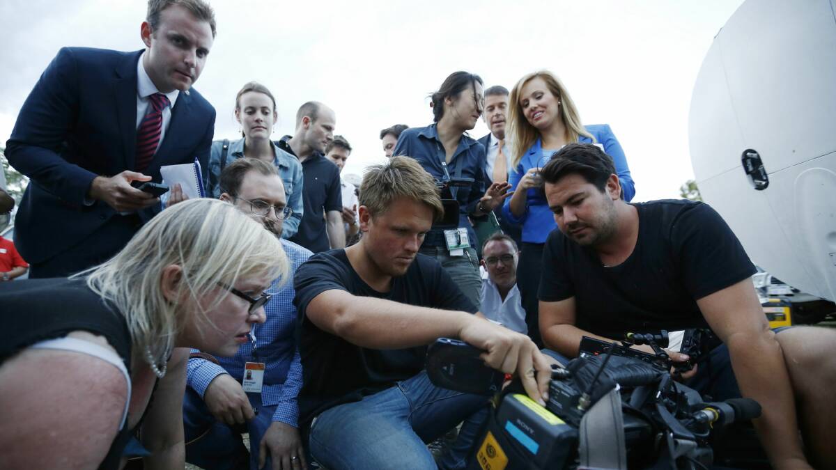 Journalists look at the monitor of a television camera crew who shot footage onboard a P-3 Orion aircraft of objects in the southern Indian Ocean, during a search of the missing Malaysian Airlines Flight MH370, after returning to RAAF Base Pearce in Bullsbrook, near Perth March 24, 2014. Photo: Reuters.
