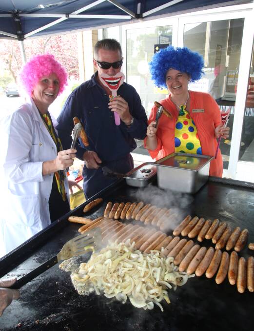 Clown bankers Jacki Leed and Michelle Kelly with Eaglehawk Lions Club BBQer Tony Harrison. Picture: PETER WEAVING