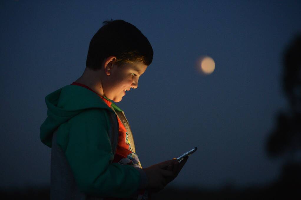 Lachlan Phillips 10 of Bendigo checks scientific data on his iPhone while watching the eclipse from the Tucker St Reserve in Golden Square
Picture: BRENDAN McCARTHY
