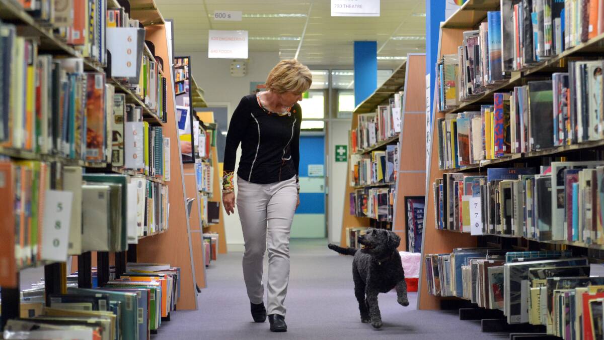  Library technician Jenn Needham and Roxy, the labradoodle who, since losing her brother, has become an unofficial library assistant. Picture: BRENDAN McCARTHY