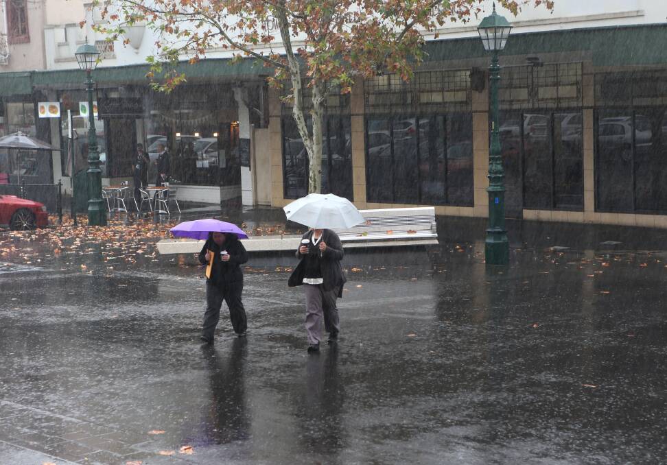 WET WEATHER: Pedestrians struggle to keep dry as they cross the road in the rain. 
